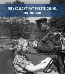 Older image from the 50's of an officer writing a ticket for a speeding to a motorist with the words "They couldn't pay tickets online, but you can.